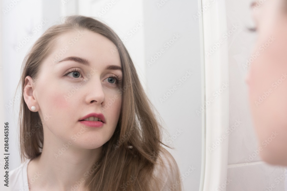 Reflection in the mirror of a pensive girl, looks in the mirror, portrait, close up Reflection in the mirror of a pensive girl, looks in the mirror, portrait, close up