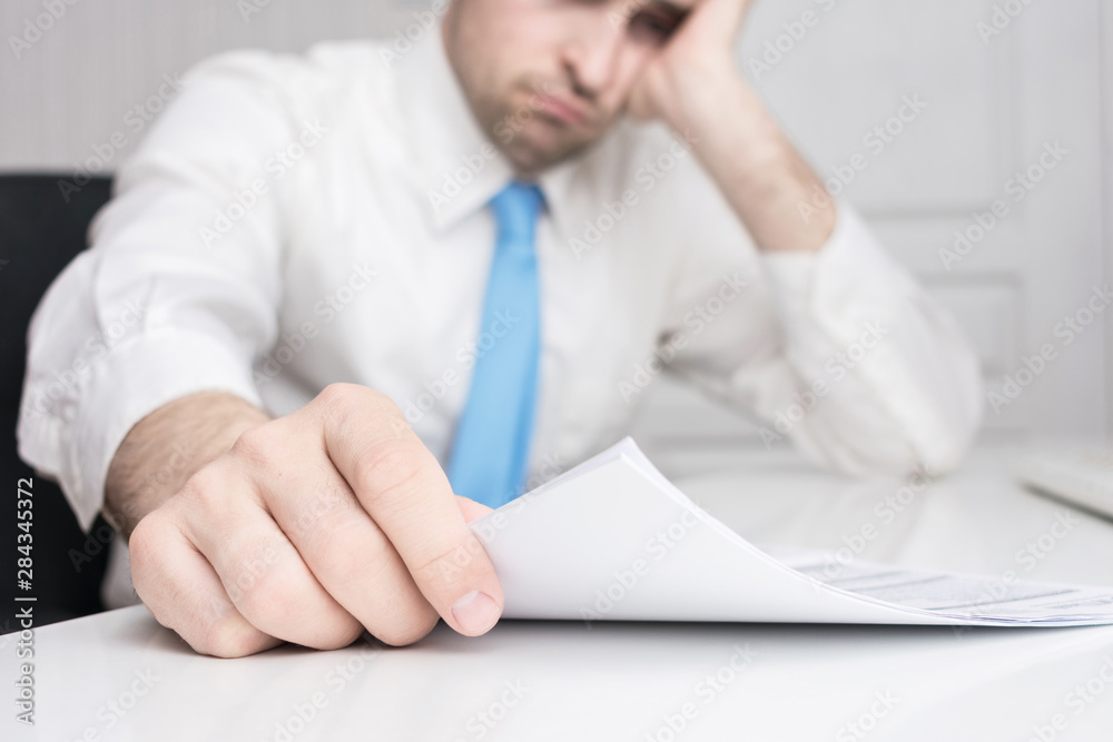 Sad businessman works in the office, documents on his desk, close up Sad businessman works in the office, documents on his desk, close up