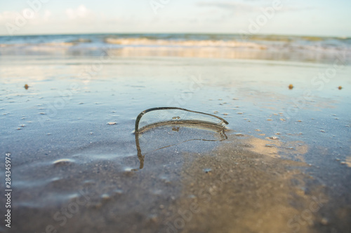 Dangerous piece of broken glass on the sand, ocean in the background on Itamaraca island - Brazil photo