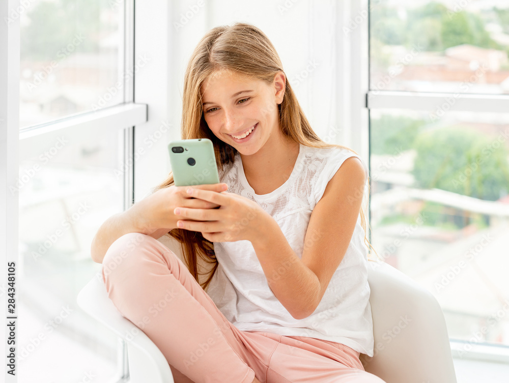 Teen girl spending leisure with her phone indoors Teen girl spending leisure with her phone indoors