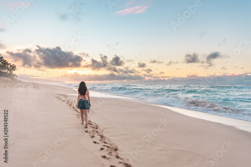 HAWAII, USA: woman walking at Sunset Beach, in Oahu, leaving footprints on the sand.