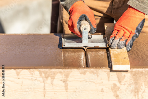 Construction Worker Using Hand Groover On Wet Cement Forming Coping Around New Pool photo