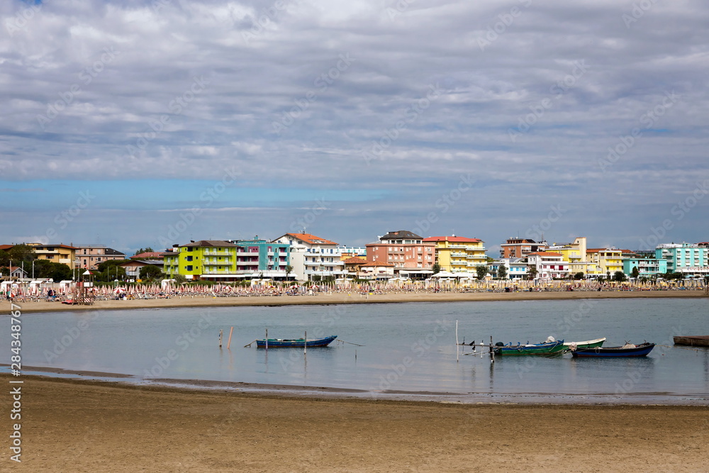 typical italian coast with the beach and the cityscape of the Caorle Italy in the background