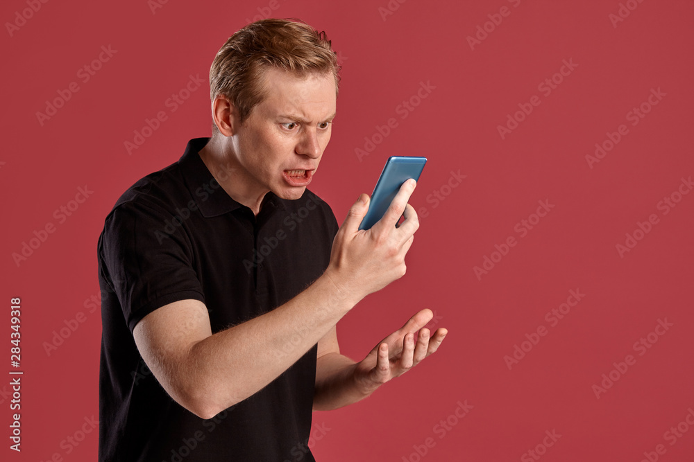 Close-up portrait of a ginger guy in black t-shirt posing on pink background. Sincere emotions. Close-up portrait of a ginger guy in black t-shirt posing on pink background. Sincere emotions.