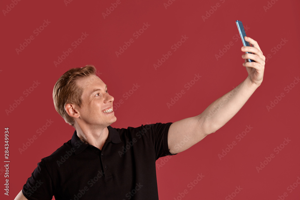 Close-up portrait of a ginger guy in black t-shirt posing on pink background. Sincere emotions.