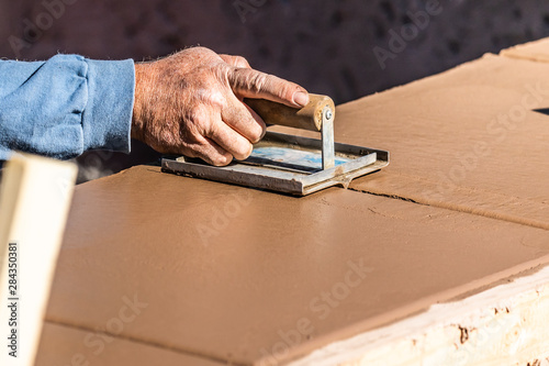 Construction Worker Using Hand Groover On Wet Cement Forming Coping Around New Pool