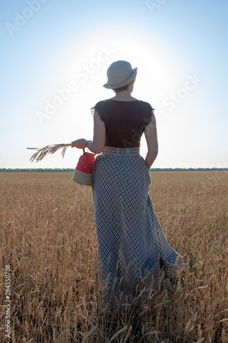 girl with ears of wheat in her hand at sunset