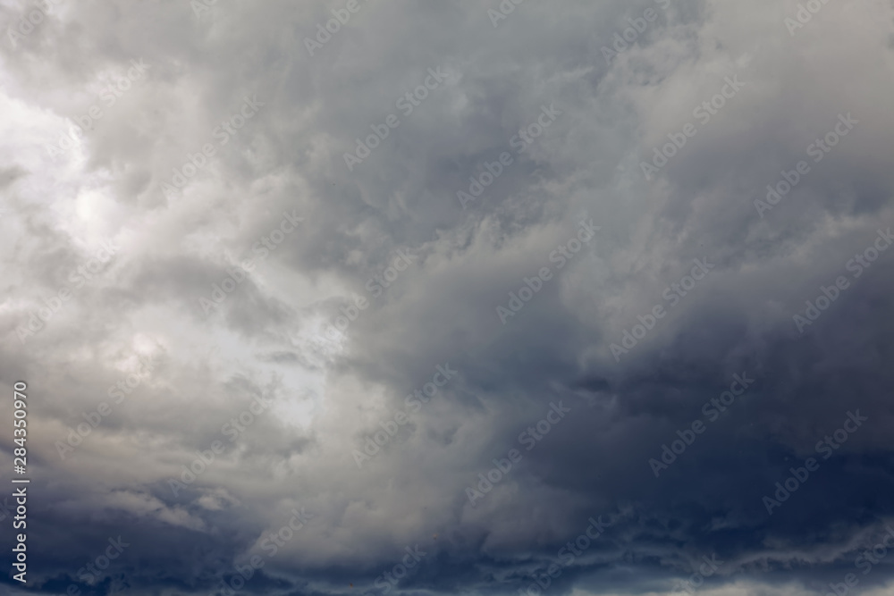 Summer dramatic clouds fly across a bright blue sky.