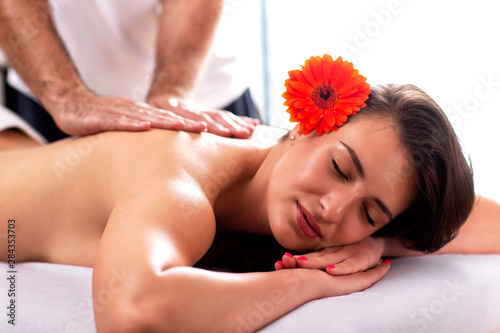 Lovely girl with flower in her hair having a massage