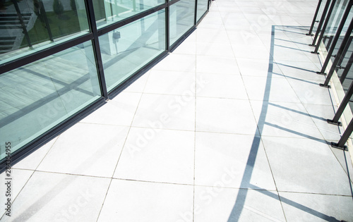 urban modern city background tile pavement floor view near glass exterior facade building and shadows from fence, copy space for text