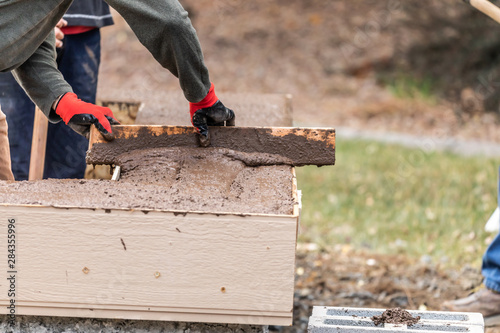 Construction Worker Leveling Wet Cement Into Wood Framing