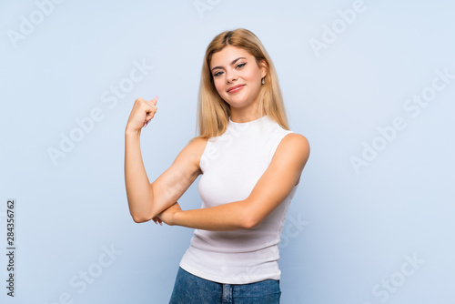 Teenager girl over isolated blue background having doubts while scratching head