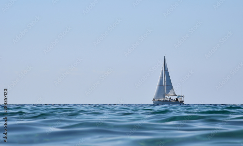 Sailing yacht in sea on background of blue sky.