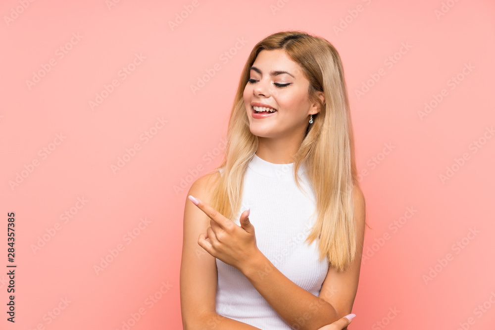 Teenager girl over isolated pink background pointing finger to the side Teenager girl over isolated pink background pointing finger to the side