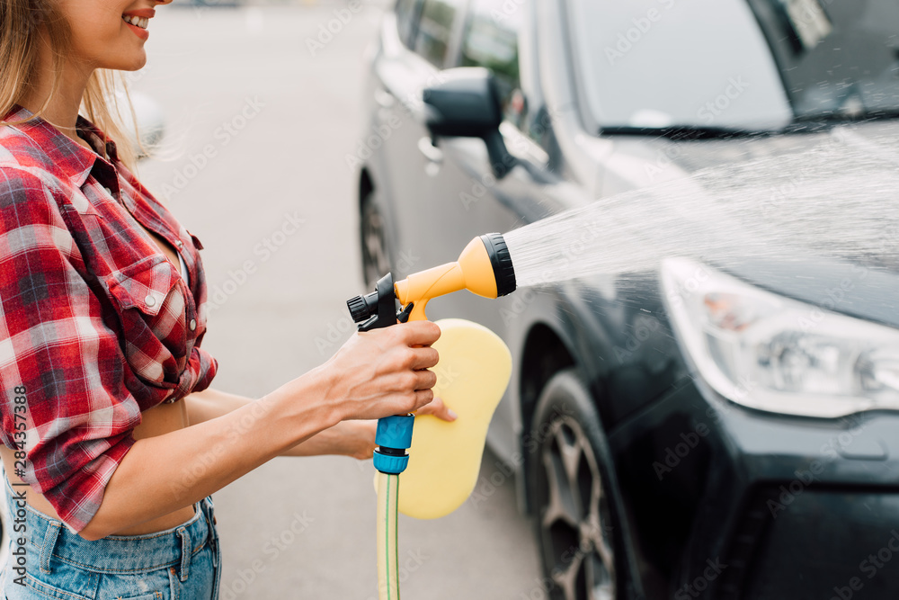 cropped view of cheerful girl washing black car cropped view of cheerful girl washing black car
