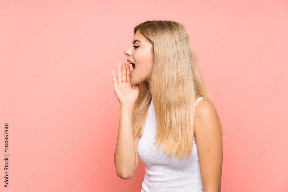 Teenager girl over isolated pink background shouting with mouth wide open Teenager girl over isolated pink background shouting with mouth wide open