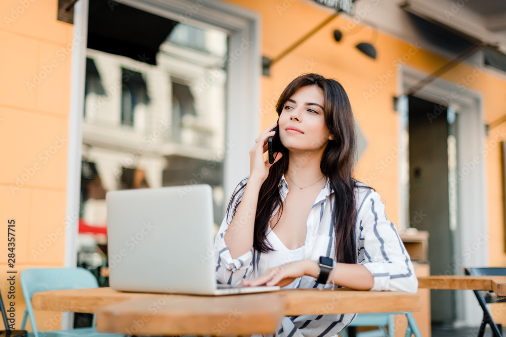 smiling woman uses laptop sitting near cafe smiling woman uses laptop sitting near cafe