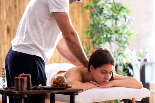 Experienced masseur massaging upper back of a pretty woman