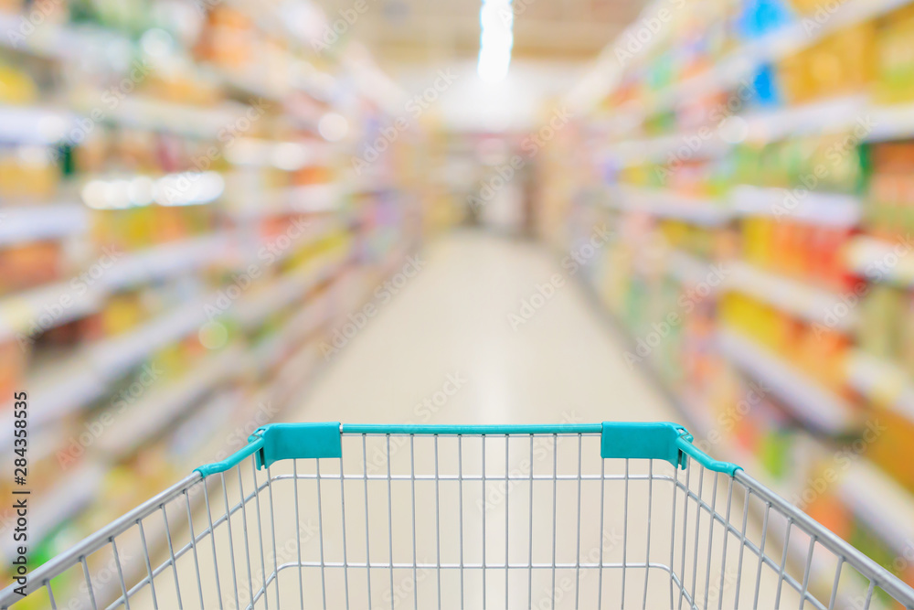 supermarket aisle with empty shopping cart and product shelves interior defocused blur background