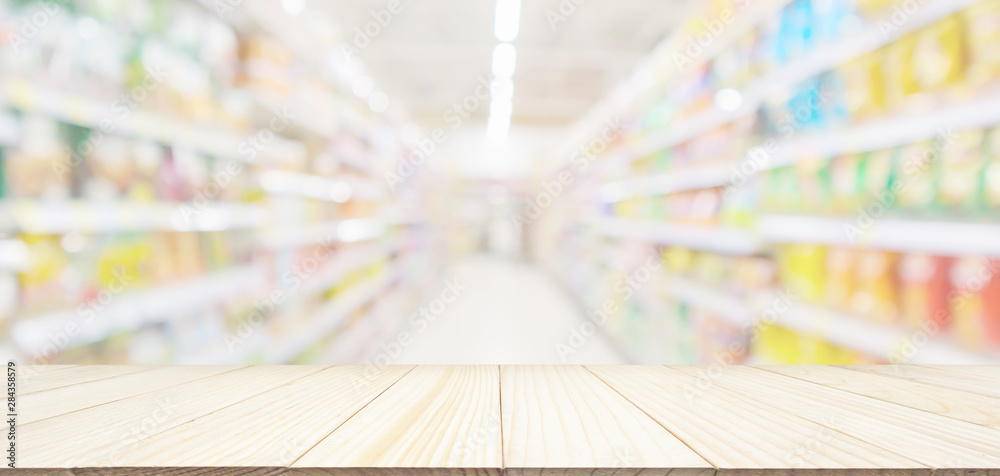 Empty wood table top with abstract supermarket grocery store aisle blurred defocused background with bokeh light for product display