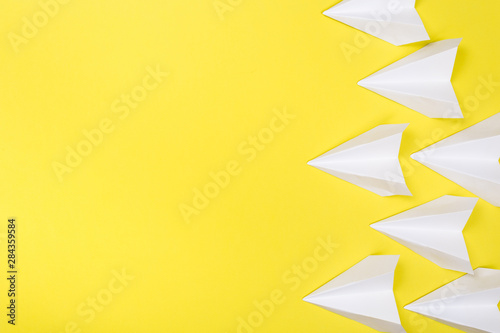 white paper airplane on yellow paper background