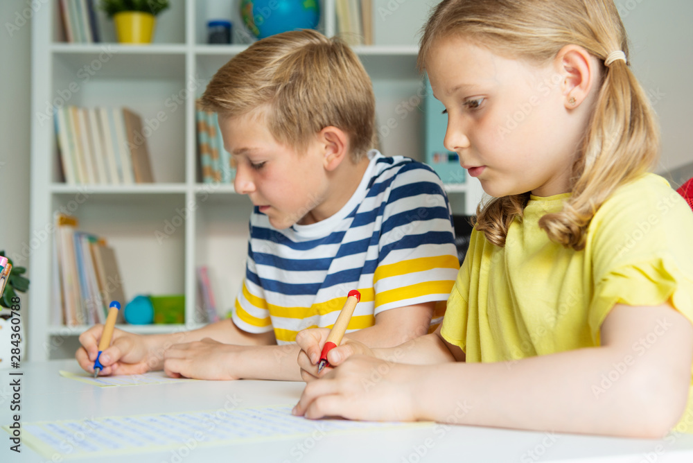 Cute schoolchildren are came back to school and learning at the table in classroom Cute schoolchildren are came back to school and learning at the table in classroom