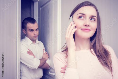 Jealous boyfriend spying on girl, his flirting on the phone with another man, portrait, close up, toned