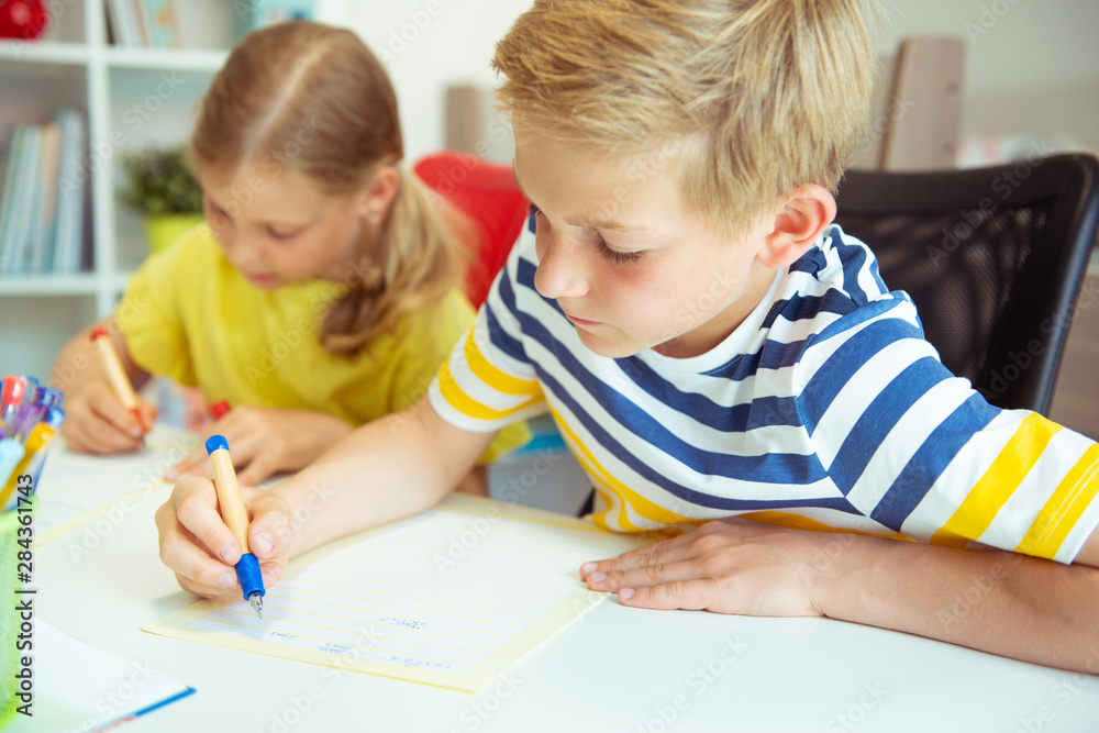 Cute schoolchildren are came back to school and learning at the table in classroom Cute schoolchildren are came back to school and learning at the table in classroom