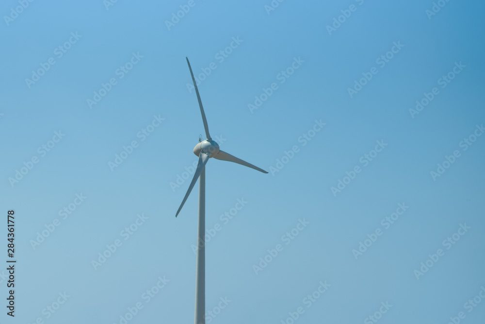 Wind turbine generating electricity with blue sky.