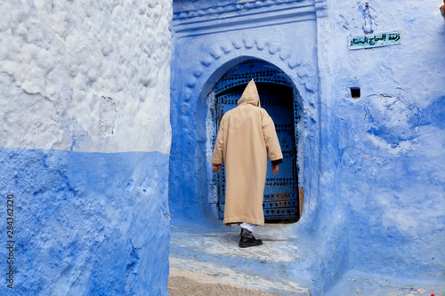 Man in doorway wearing a djellaba, Chefchaouen, Morocco photo