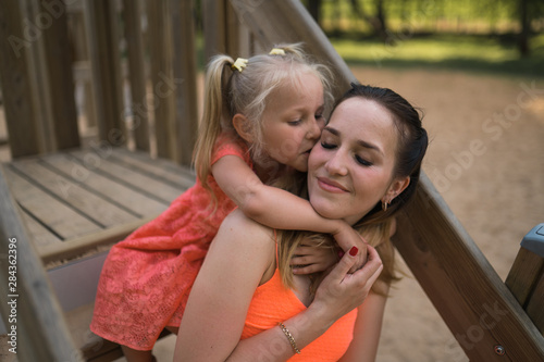 Happy mother playing with her little baby girl daughter and having fun - Young caucasian white mom wearing summer bright vivid color dress - Happinness family concept photo