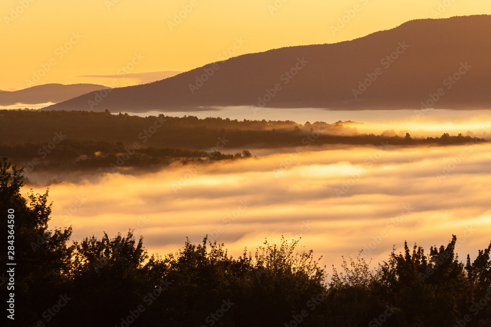 Early morning sunrise of a fog enshrouded valley, Stowe, Vermont, USA