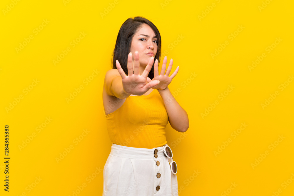 Young Mexican woman over isolated yellow background nervous stretching hands to the front Young Mexican woman over isolated yellow background nervous stretching hands to the front