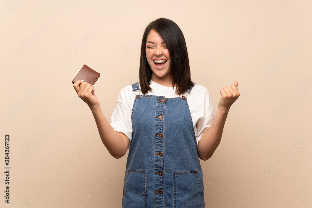 Young Mexican woman over isolated background holding a wallet Young Mexican woman over isolated background holding a wallet