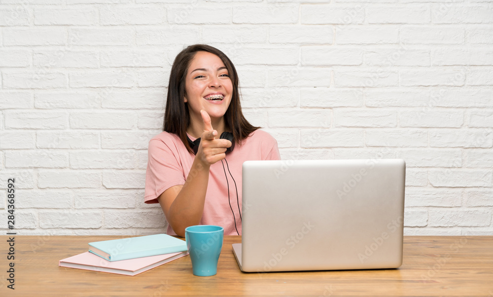Young Mexican woman with a laptop points finger at you Young Mexican woman with a laptop points finger at you