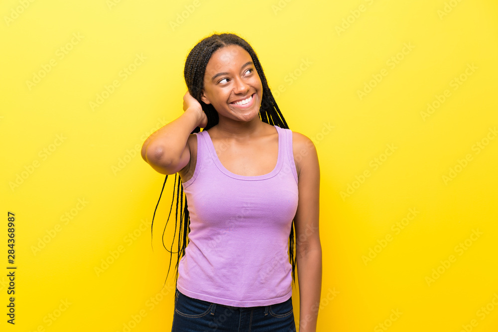 African American teenager girl with long braided hair over isolated yellow wall thinking an idea African American teenager girl with long braided hair over isolated yellow wall thinking an idea
