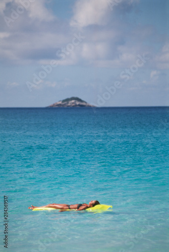 Seychelles, Praslin Island, Girl floats on mattress © Nik Wheeler/Danita Delimont