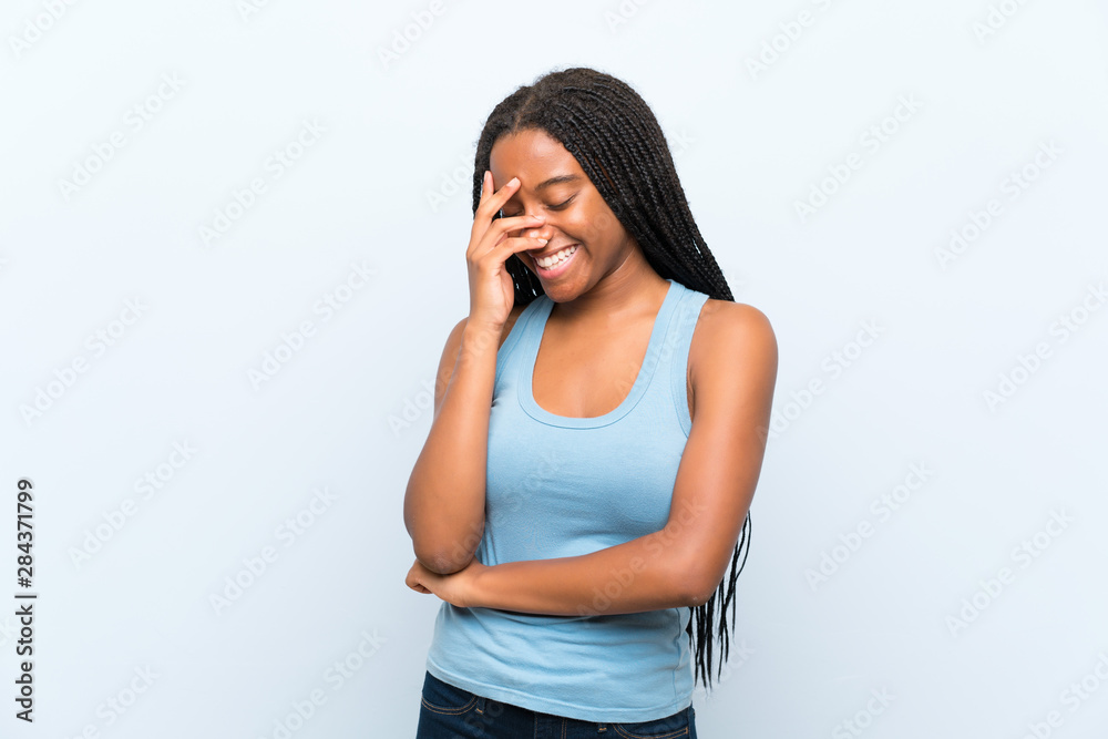 African American teenager girl with long braided hair over isolated blue background laughing African American teenager girl with long braided hair over isolated blue background laughing