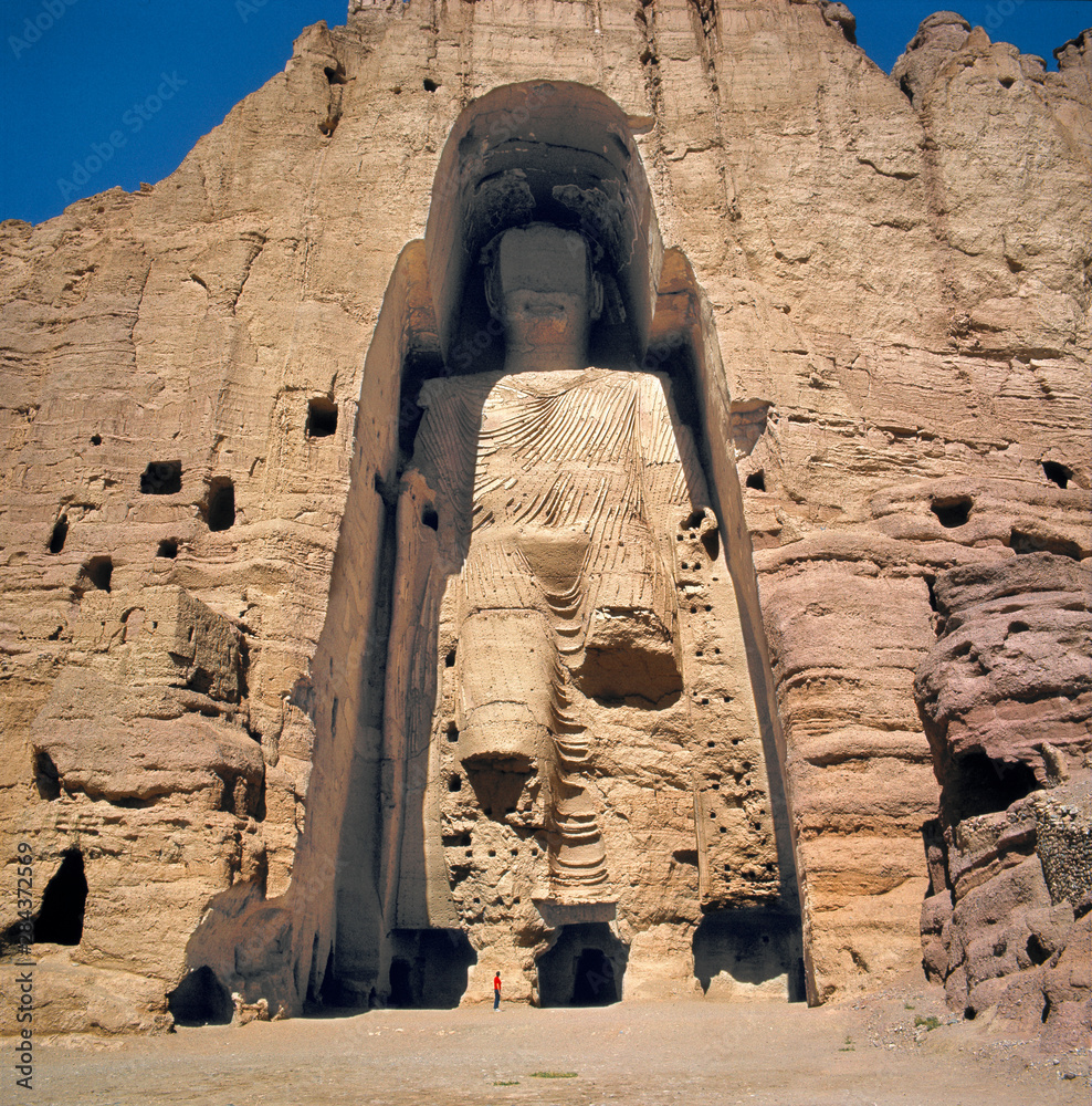 Naklejka premium Afghanistan, Bamian Valley. A person stands at the base of the Great Buddha in the Bamian Valley, a World Heritage Site, in Afghanistan.