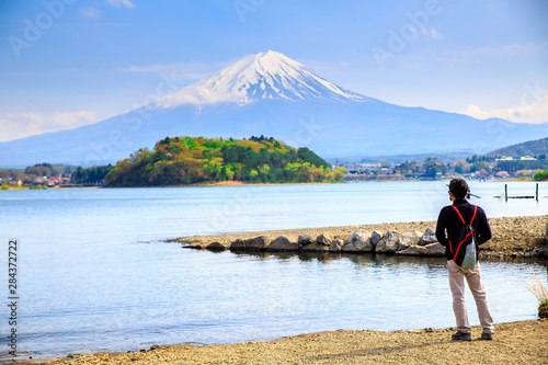 Mt diamond fuji with snow and flower garden along the lake walkway at Kawaguchiko lake in japan  Mt Fuji is one of famous place in Japan. A man stand and looking far away.