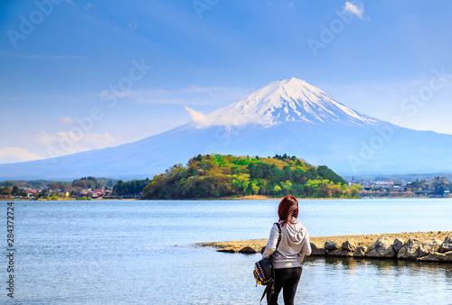 Mt diamond fuji with snow and flower garden along the lake walkway at Kawaguchiko lake in japan, Mt Fuji is one of famous place in Japan. A girl stand and looking far away.