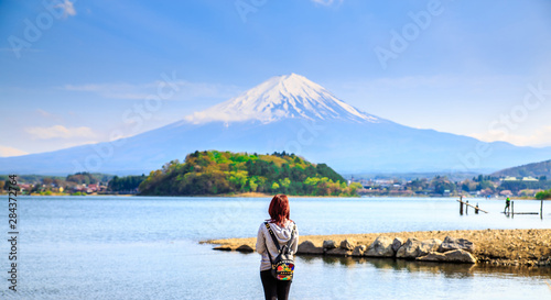 Mt diamond fuji with snow and flower garden along the lake walkway at Kawaguchiko lake in japan, Mt Fuji is one of famous place in Japan. A girl stand and looking far away.