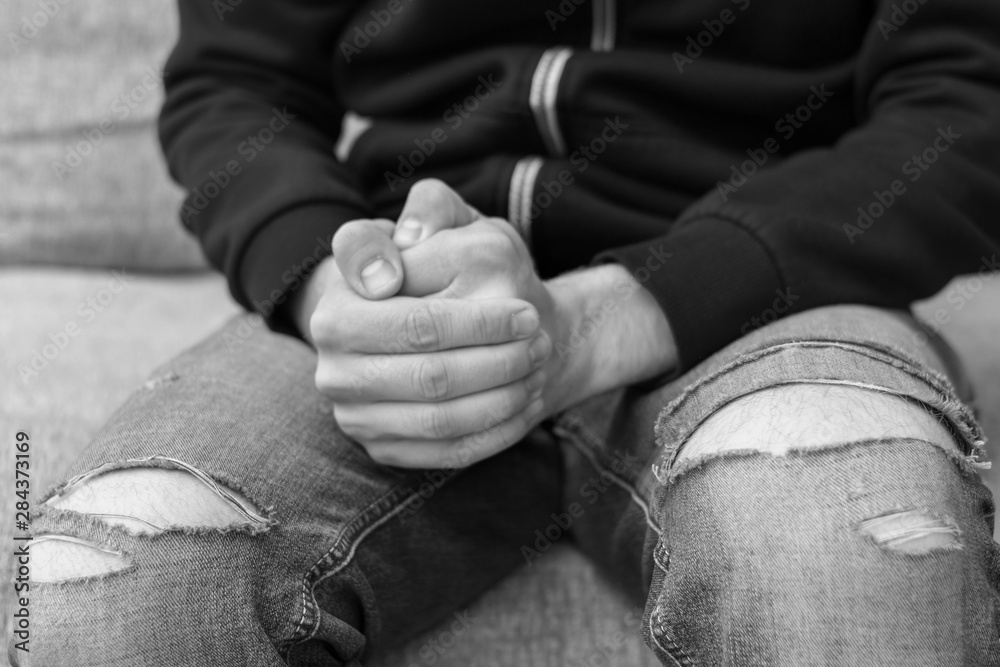 A poor man in torn trousers in despair, hands man, close up, black and white photo, the concept of poverty
