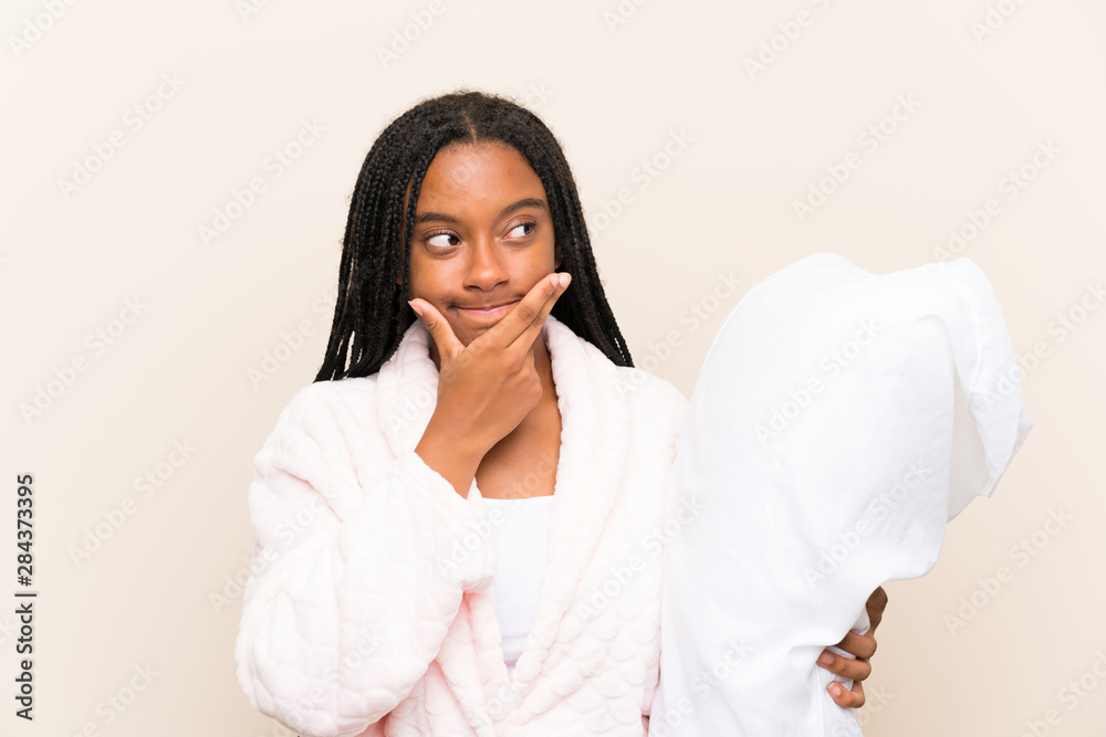 African American teenager girl with long braided hair in pajamas over isolated background thinking an idea African American teenager girl with long braided hair in pajamas over isolated background thinking an idea
