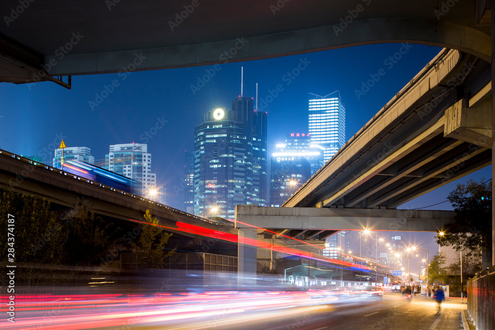 Fototapeta premium China, Beijing, Highway overpass and glowing steel and glass office towers along Third Ring Road in central business district at night