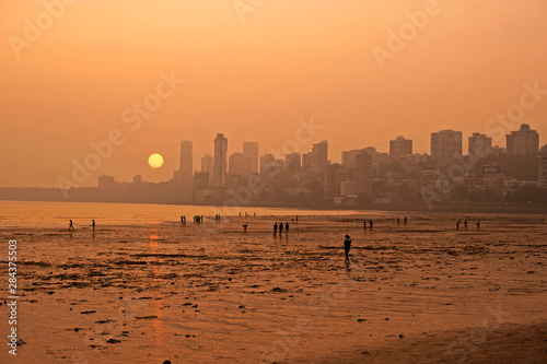 India, Maharashtra, Mumbai, Chowpatty beach, sunset with red sun coming down under the skyline photo