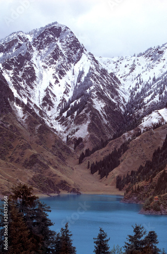 China, Xinjiang, Heavenly Lake. Lovely Heavenly Lake lies in the snowy shadow of the Tien Shan Range, Xinjiang, China.