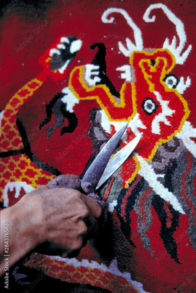 Obraz premium Asia, India, Darjeeling. This trimmer's deft hands and shiny shears perfect a carpet at the Tibetan Refugee Center, Darjeeling, India.