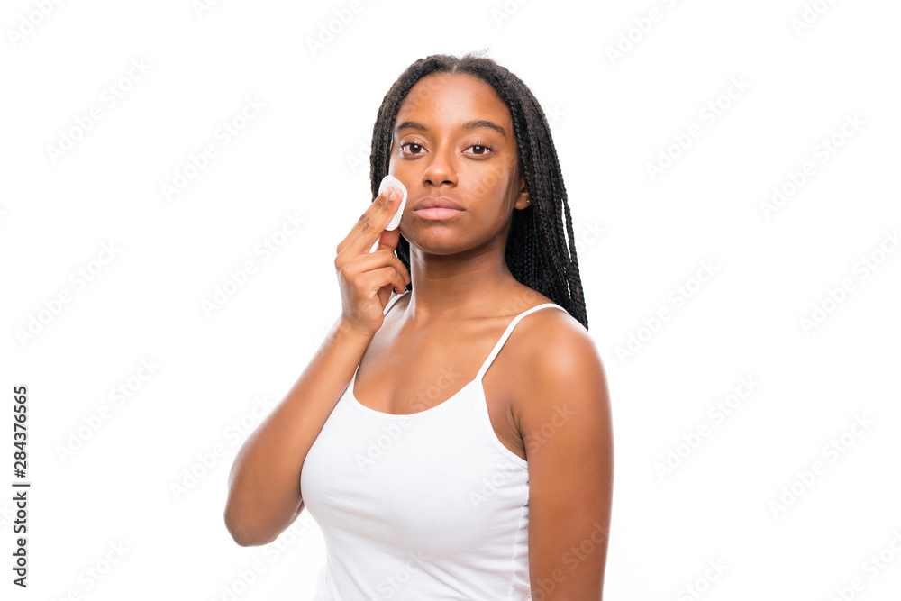 African American teenager girl with long braided hair removing makeup from her face with cotton pad African American teenager girl with long braided hair removing makeup from her face with cotton pad