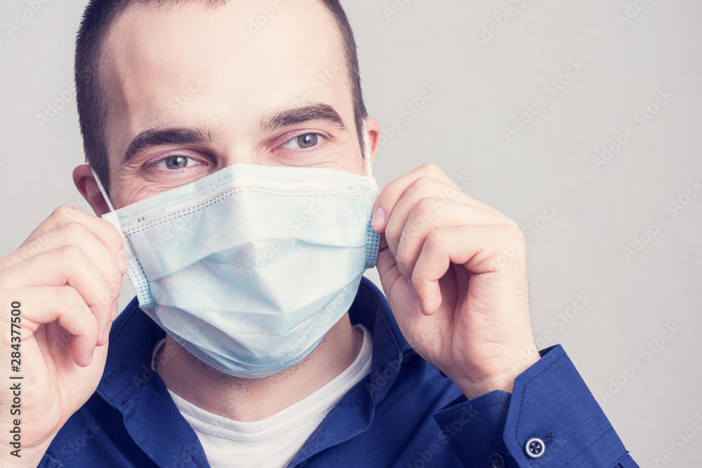 Joyful male puts a medical mask and smiling, portrait, close up, toned, health care concept Joyful male puts a medical mask and smiling, portrait, close up, toned, health care concept